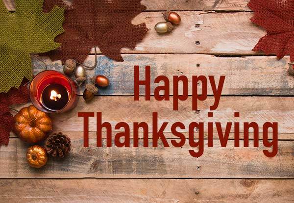 Happy Thanksgiving. Decorative leaves, pumpkins, and acorns are scattered on a wooden table